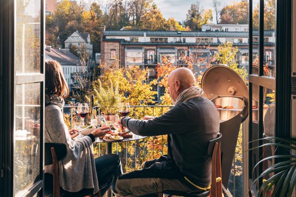 Man och kvinna äter grillad mat på balkong bredvid Cone Kolgrill