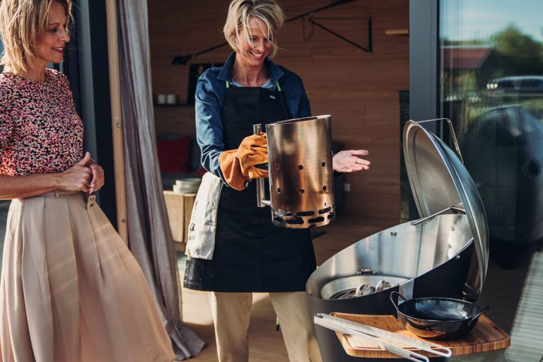 Kvinna använder skorstenständare för att tända Cone Kolgrill