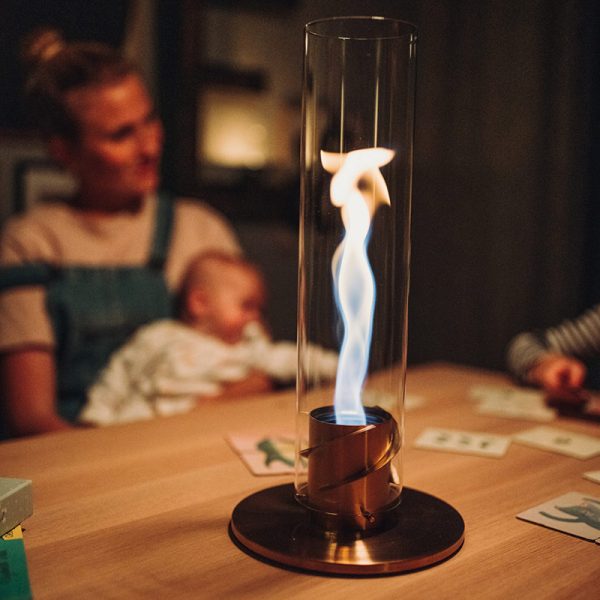 Höfats Spin Eldlykta 90 guld brinner på bord med mamma och bebis i bakgrunden