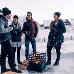 Kompisgäng värmer sig vintertid runt Höfats Cube Eldkorg och Kolgrill svart