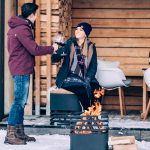 Höfats Cube Eldkorg och Kolgrill svart brinner vintertid vid par som skålar