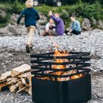 Höfats Cube Eldkorg och Kolgrill svart brinner på campingplats med kompisgäng i bakgrunden