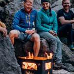 Par eldar utomhus mot bergsvägg med Höfats Beer Box eldkorg som ger lågor ifrån sig
