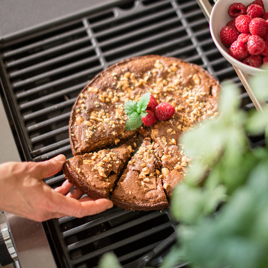 Hand tar en bit grillad kladdkaka med mjölkchoklad och jordnötter ovanpå grill