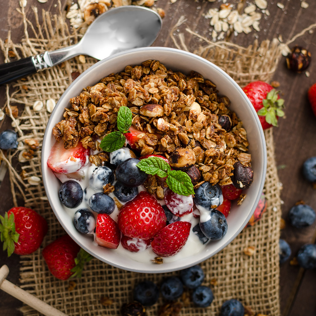 Grillad granola med yoghurt, jordgubbar, blåbär och mynta i vit skål