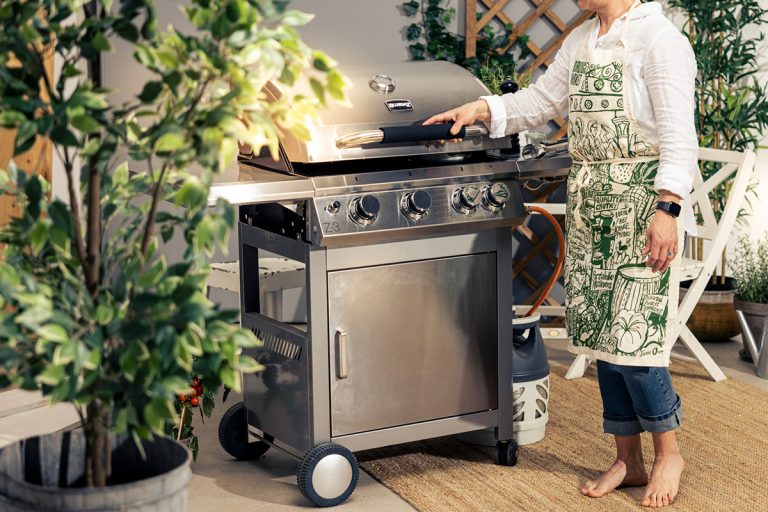 Kvinna lyfter lock på Bluegaz Z3 Gasolgrill