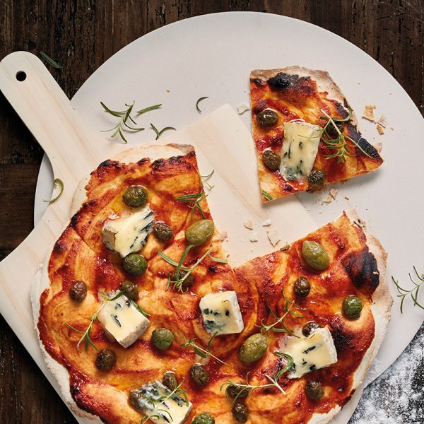 Funktion pizzaspade på vit tallrik med gorgonzolapizza med gröna och svarta oliver närbild
