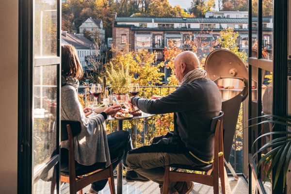 Par sitter och äter på balkong bredvid grill