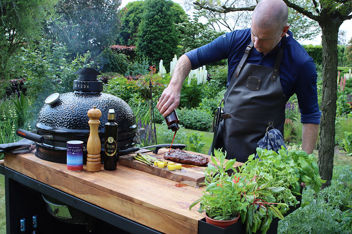 Man häller bbq-sås på kött inför kamadogrillning