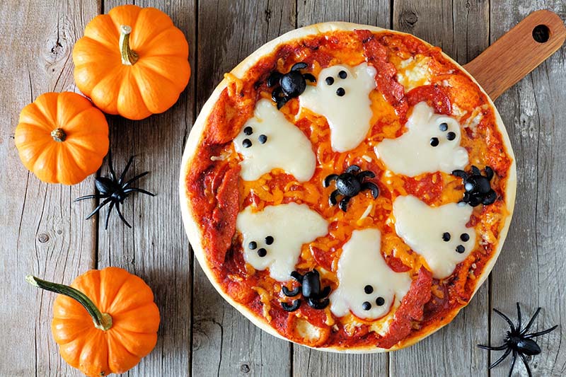 Grillad spökpizza med tomatsås, salami, svarta oliver som spindlar och mozzarella som spöken