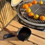 Bluegaz Premium Gjutjärnsgryta med grillpensel med örtglaze står på sidobord bredvid grill