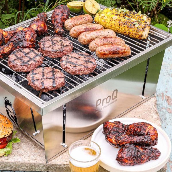 Hamburgare, korv, kycklingklubbor och majs grillas på ProQ Flatdog Bärbar grill