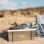 ProQ Flatdog Bärbar grill på stranden framför picknickfilt