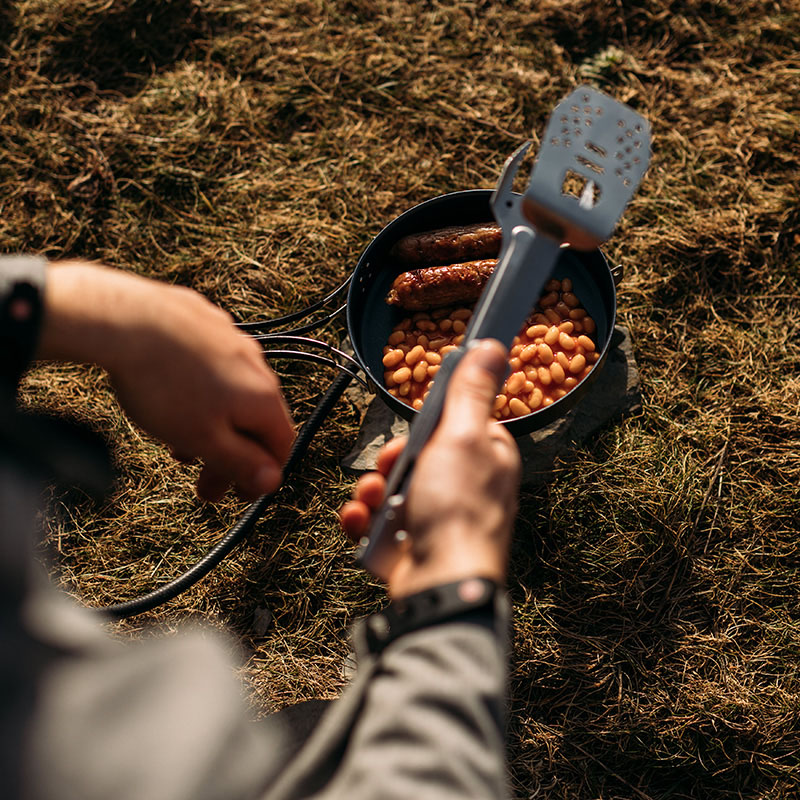 Lagar korv och vita bönor i tomatsås under utflykten med hjälp av ProQ Multiverktyg för grill