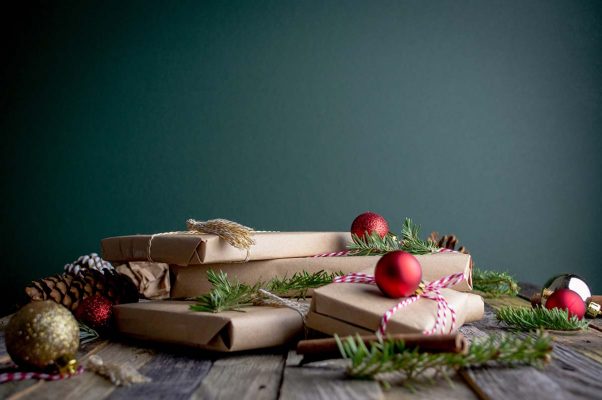 Julklappstips 2022 banner - Mörkgrön julbanner med inslagna paket, röda julkulor och granris på träbord