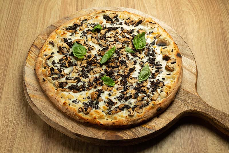 Pizza Bianco med tryffel och svamp på rund skärbräda i trä