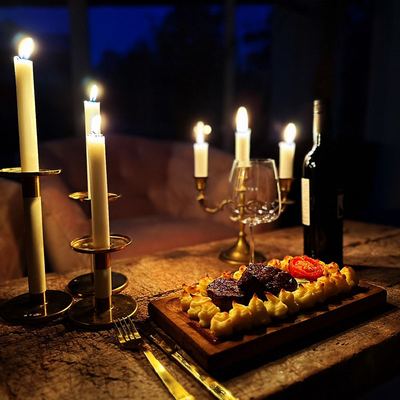 Grillad plankstek med duchessetoppar serverad på bord med tända ljus runt om