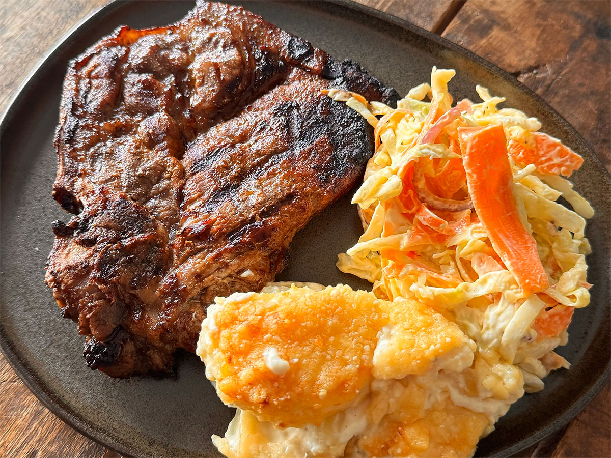 Grillad fläskkarré med hemmagjord coleslaw och potatisgratäng på grå tallrik