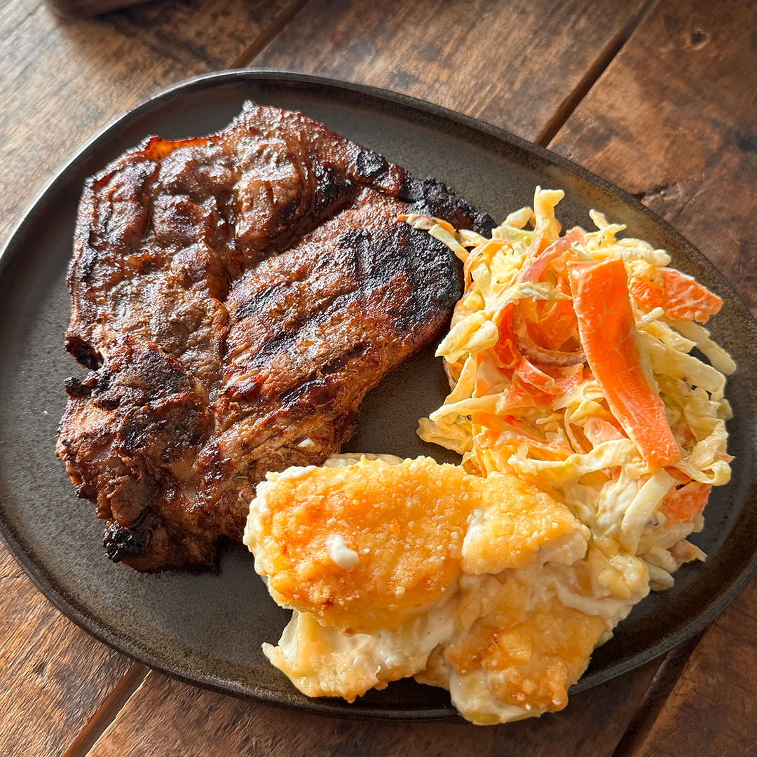 Grillad fläskkarré med hemmagjord coleslaw och potatisgratäng på grå tallrik