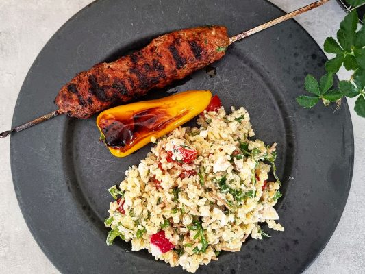 Grillad cevapcici med bulgursallad serverat på svart tallrik