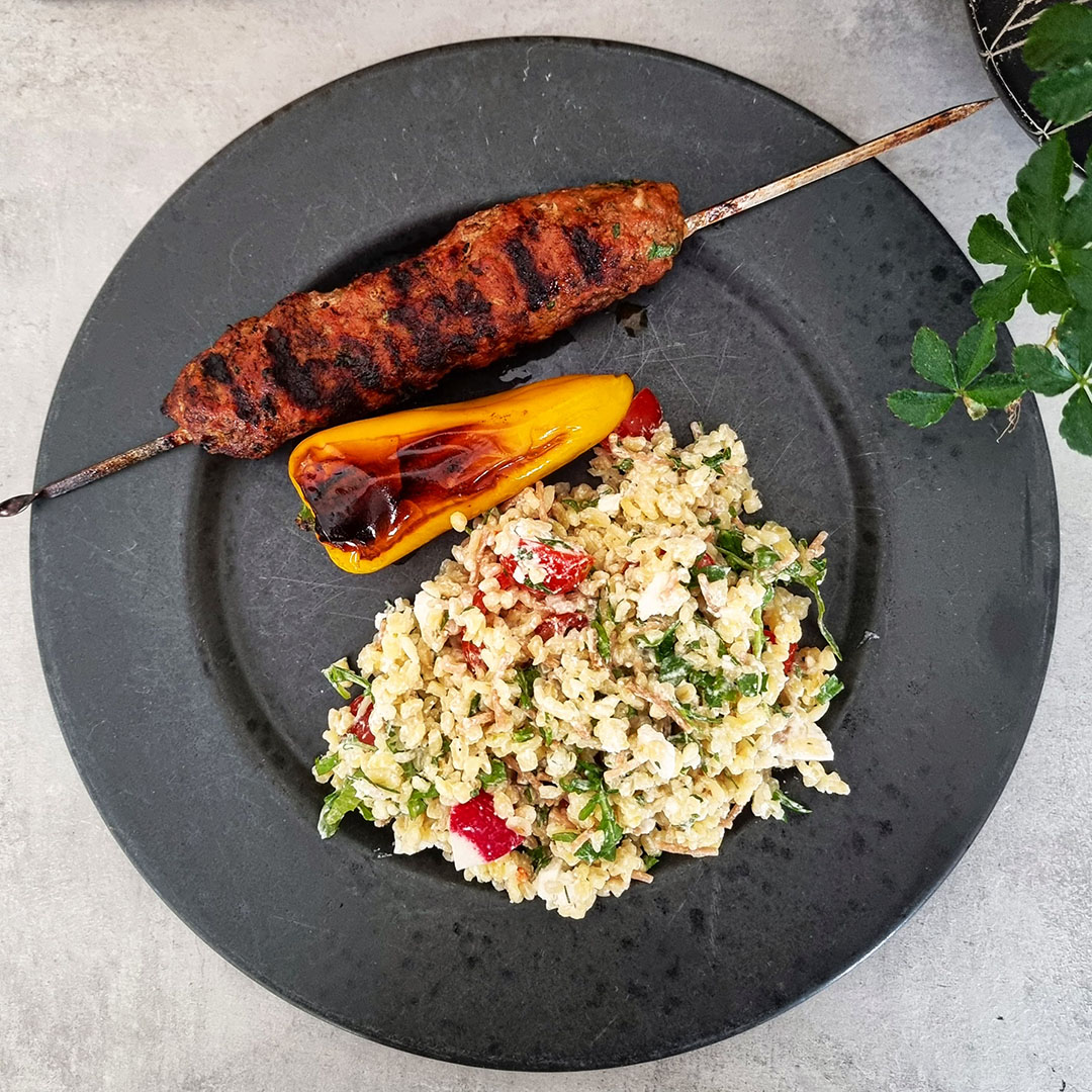 Grillad cevapcici med bulgursallad serverat på svart tallrik