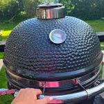 Hand på väg för att öppna locket på Bluegaz Kyoto Kamado Large