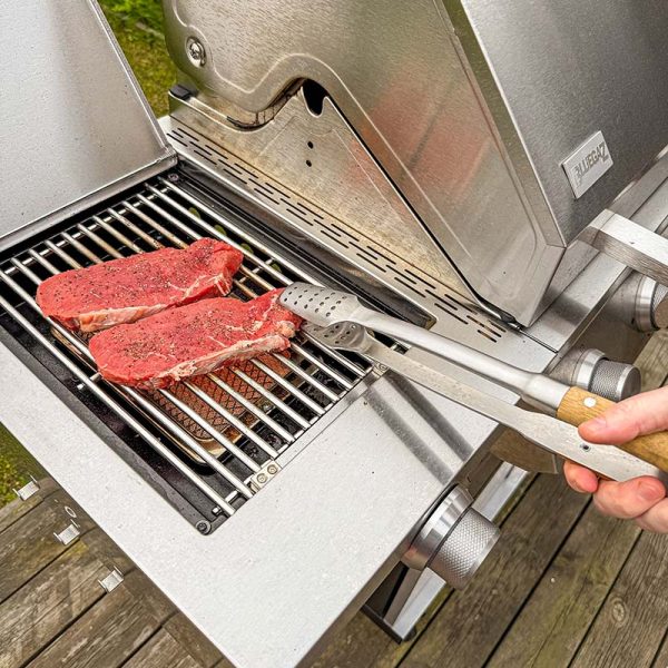 Använder Bluegaz Elite Grilltång för att lyfta köttbit