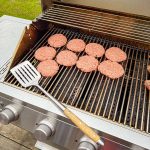 Bluegaz Elite Grillspade ligger på grillgaller bredvid burgare