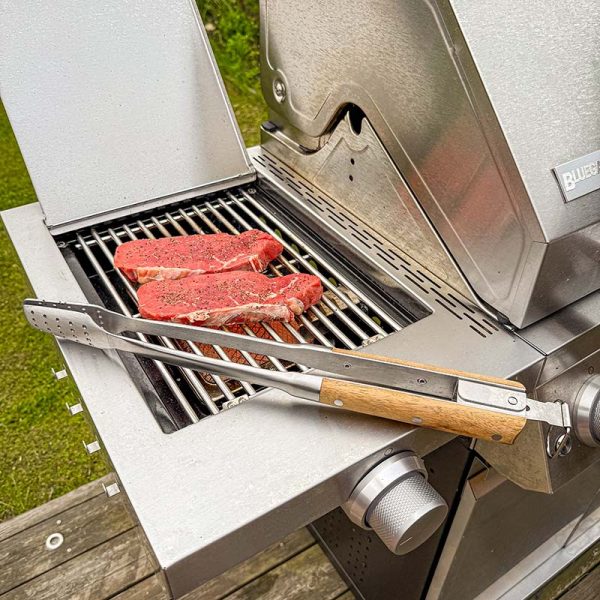 Bluegaz Elite Grilltång ligger på sizzle burner bredvid kött