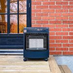 Bluegaz Kalahari Mini Gasolkamin står på trädäck framför tegelvägg