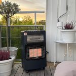 Bluegaz Tabernas Gasolkamin med fläkt står på trädäck bredvid vita krukor