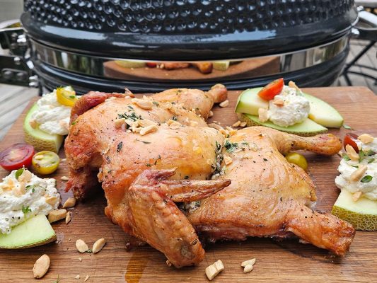 Grillad hel kyckling på skärbräda framför kamadogrill