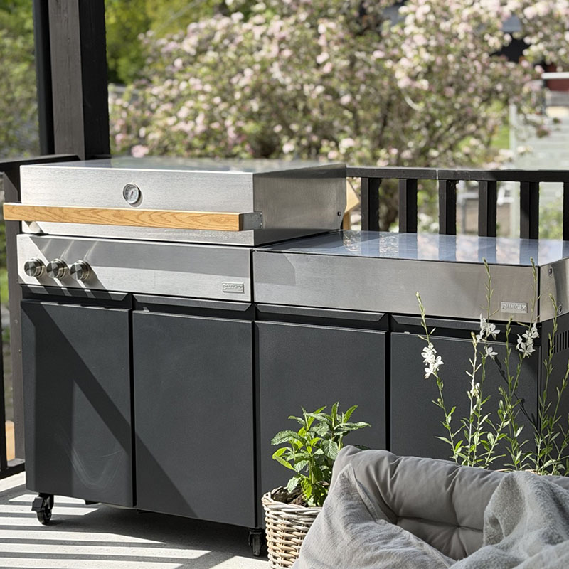 Bluegaz Z Gasolgrill med Z Sidomodul på uteplats med svart staket och träd i bakgrunden