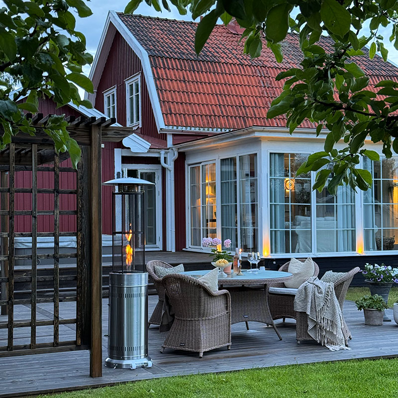 Bluegaz Teide Terrassvärmare på trädäck framför röd villa med gren i förgrunden
