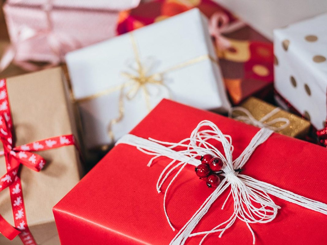 Hög med julklappar med rött paket i förgrunden