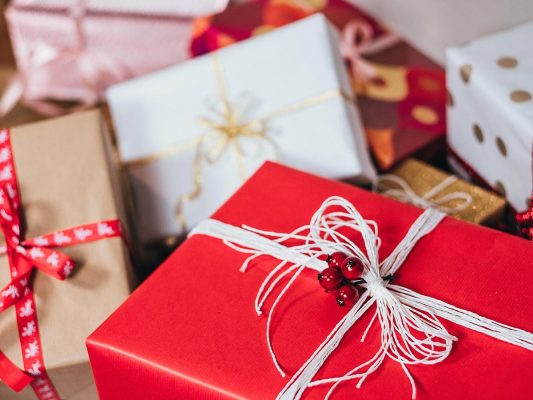 Hög med julklappar med rött paket i förgrunden